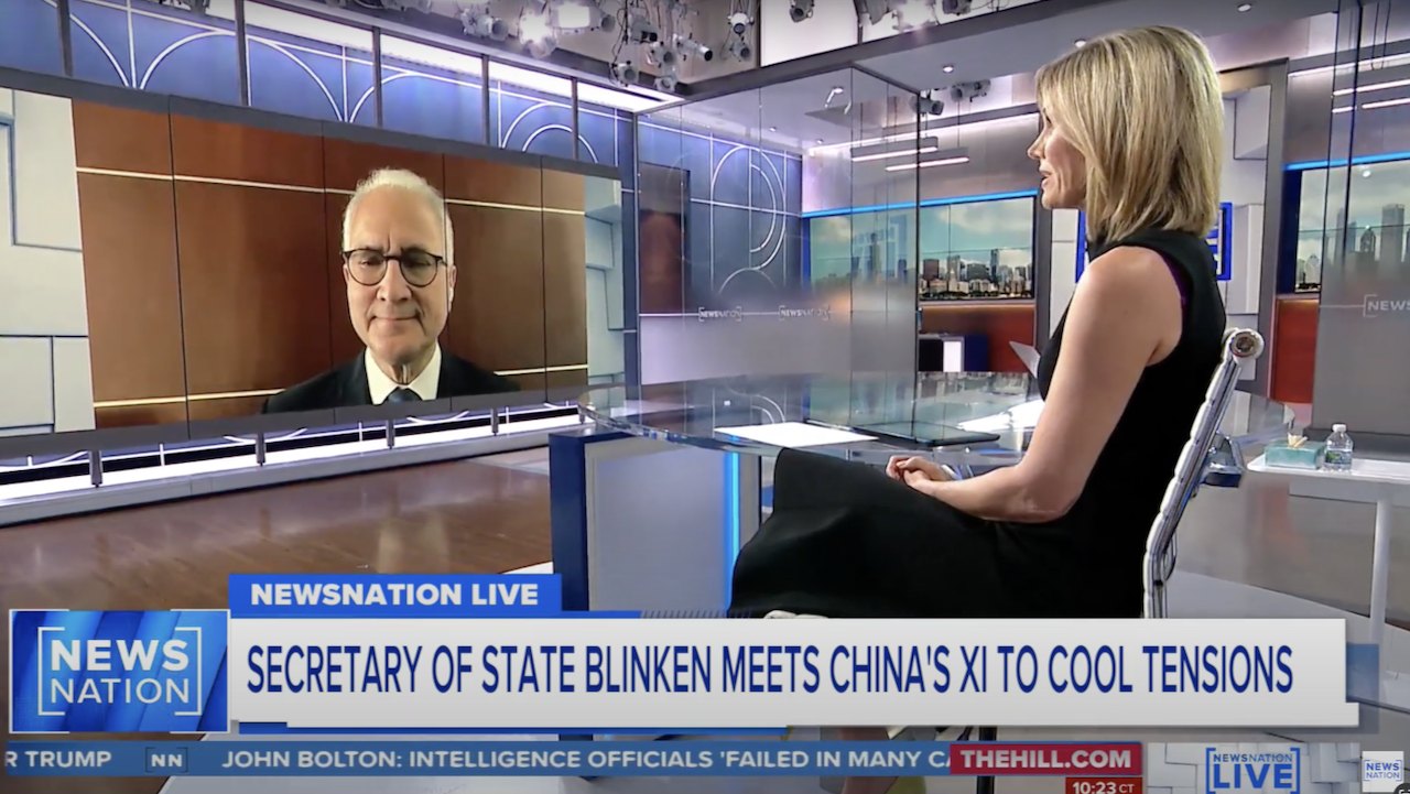 A female news anchor sits at a desk interviewing a man on a large screen in a modern TV studio. The headline reads, Secretary of State Blinken Meets Chinas Xi to Cool Tensions, on NewsNation Live.