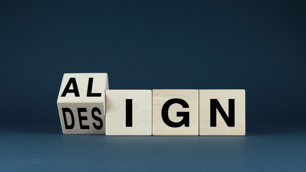 Four wooden blocks spell out DESIGN, but the first two blocks are stacked, so only AL is visible above DES, aligning to form the word ALIGN vertically and SIGN horizontally on a dark blue background.
