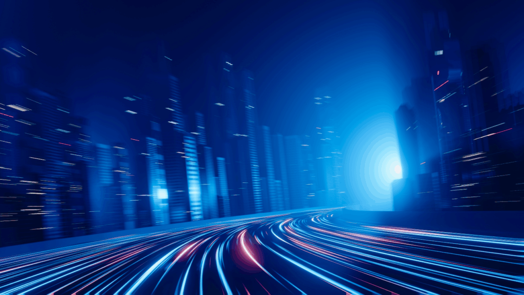 Futuristic cityscape at night with tall skyscrapers and glowing light trails on a curving road, suggesting high-speed motion and advanced technology. The scene is dominated by blue tones and dynamic lighting effects.