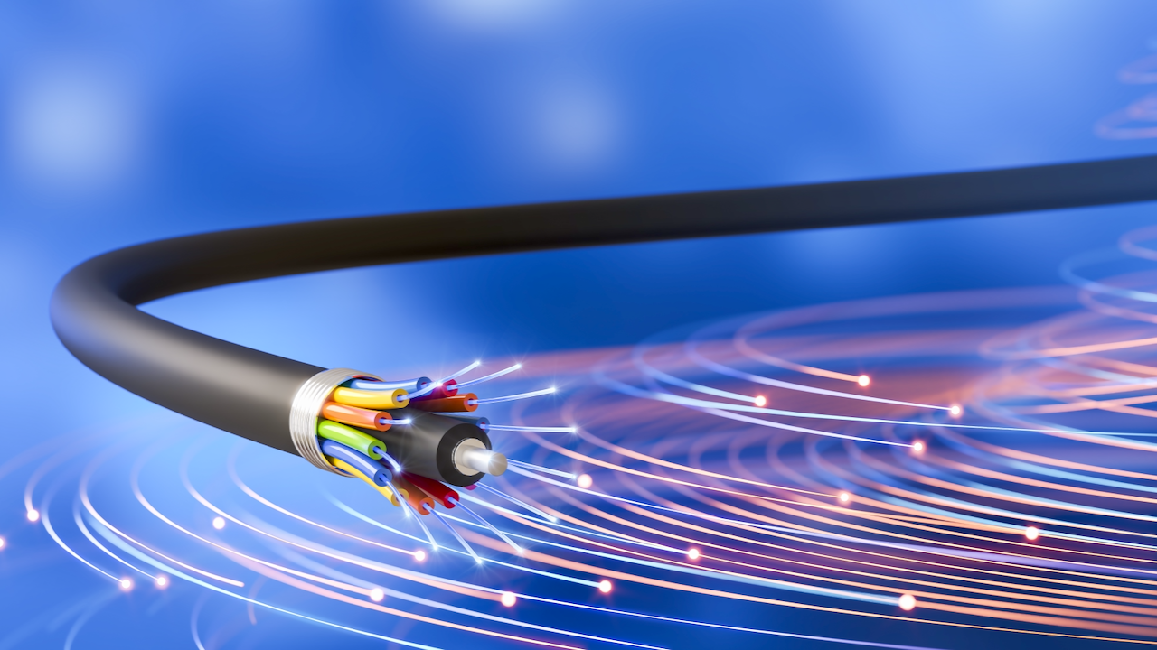 A close-up view of a fiber optic cable with exposed colorful internal wires, set against a blue background with glowing light streaks representing high-speed data transmission.