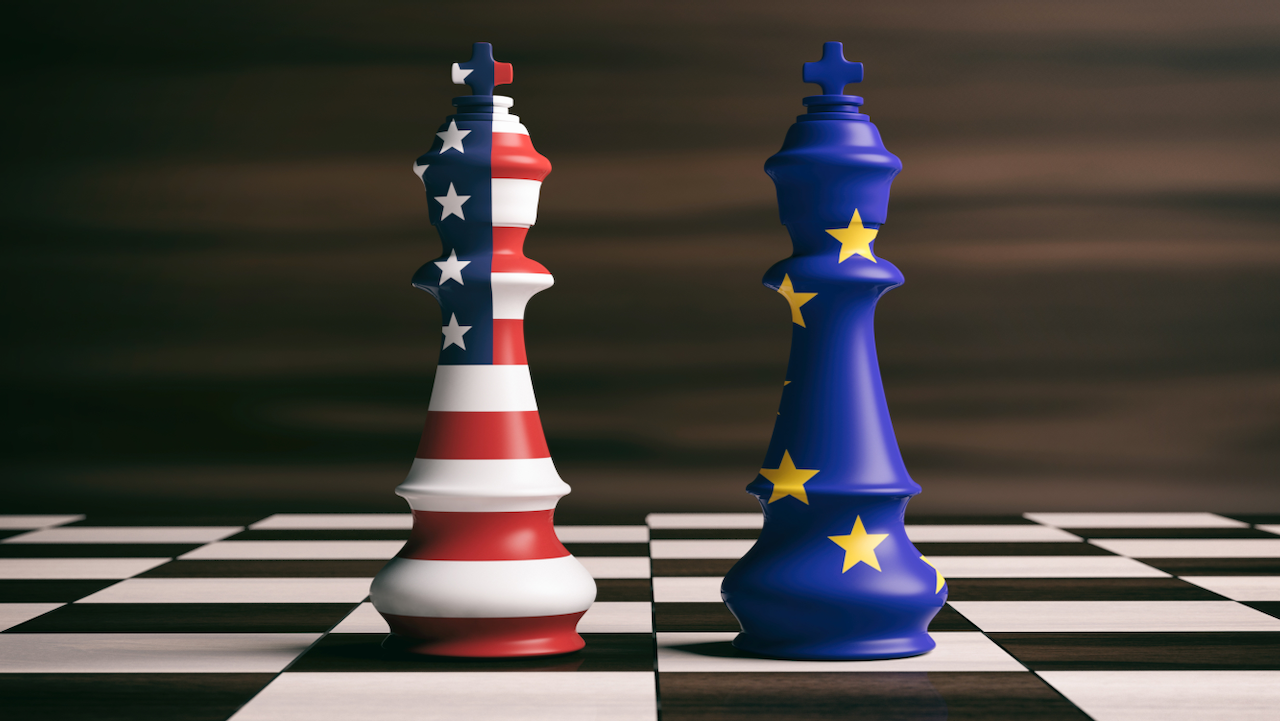 Two chess kings stand on a chessboard; one is decorated with the American flag, and the other with the European Union flag, symbolizing strategic competition or relations between the US and EU.